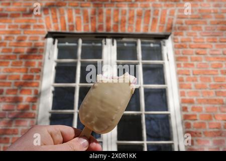 Abgeschnittene Hand, die Eis am Gebäude hält Stockfoto