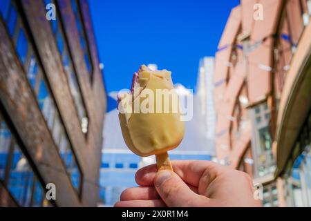 Abgeschnittene Hand, die Eis am Gebäude hält Stockfoto