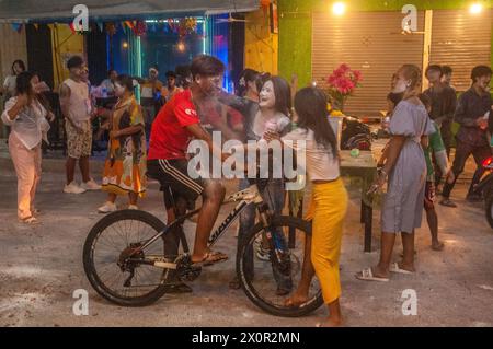 2 kambodschanische Frauen schmieren beim kambodschanischen Neujahrsfest Talkumpuder/Babypuder auf das Gesicht eines Radfahrers. Phnom Penh, Kambodscha. © Kraig Lieb Stockfoto