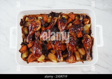 Gebratene Hähnchenschenkel mit Kartoffeln, Süßkartoffel, rote Zwiebeln Stockfoto