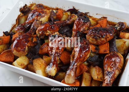 Gebratene Hähnchenschenkel mit Kartoffeln, Süßkartoffel, rote Zwiebeln Stockfoto