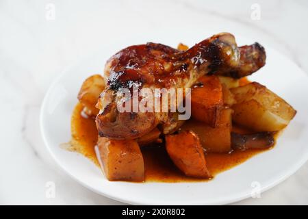 Gebratene Hähnchenschenkel mit Kartoffeln, Süßkartoffel, rote Zwiebeln Stockfoto