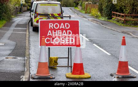 Schild „Road Ahead Closed“ (Straße vor geschlossen) mit Highway Maintenance-Van – Metallweiß auf rotem Text Stockfoto