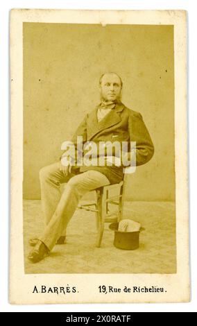 Original und klarer französischer Albumendruck aus den 1860er Jahren - Carte de Visite (Visitenkarte oder CDV) eines französischen Genltleman, der auf einem Stuhl sitzt und neben ihm einen Hut hat. Aus dem Fotostudio von A Barres, Rue de Richelieu, Paris, Frankreich. Etwa Ende der 1860er/Anfang der 1870er Jahre Stockfoto