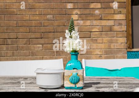 Lagerhaus im Freien. Bei sommerlichen Sonneneinflüssen stehen Stühle und Tische im Freien zur Verfügung. Vase mit den Blumen auf dem Tisch für Sommer-Café. Stockfoto