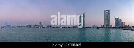 Ein Bild der Abu Dhabi Beach Front, von der anderen Seite des Wassers gesehen, bei Sonnenuntergang, mit der St. Regis Abu Dhabi Hotel, die Etihad Towers und das Abu DHA Stockfoto