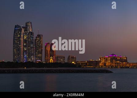 Ein Bild der Etihad Towers und des Emirates Palace Mandarin Oriental Hotel bei Sonnenuntergang. Stockfoto