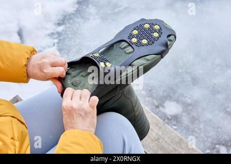 Montage der rutschfesten Schuhgriffe mit Stollen an der Unterseite des Schuhs. Stockfoto