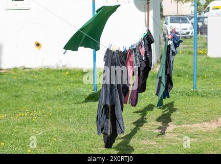 Wäschetrocknung an einer Schnur zwischen Blockhäusern. Die ersten sonnigen und windigen Frühlingstage. Stockfoto