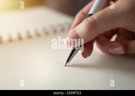 Die Hand einer Frau, die einen Stift auf dem Notizbuch hält. Bildungs- und Arbeitskonzept. Stockfoto