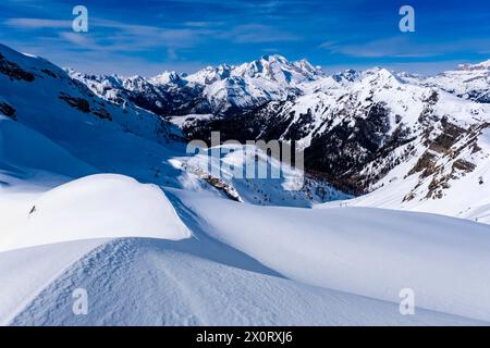 Schneetreiben schafft kunstvolle Strukturen rund um den Giau Pass im Winter, alpine Dolomitenlandschaft und schneebedeckte Gipfel der Marmolada Gruppe in der Ferne Stockfoto