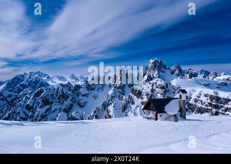 Die Kapelle Cappella degli Alpini im Naturpark Tre Cime im Winter, die alpine Dolomitenlandschaft und die Gipfel von Cadini di Misurina in der Ferne. Stockfoto