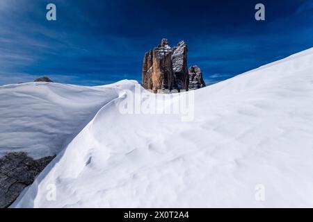 Schneeschwehungen schaffen kunstvolle Strukturen im Naturpark Tre Cime im Winter, den Gipfeln des Tre Cime di Lavaredo in der Ferne, von der Forcella Lavar aus gesehen Stockfoto