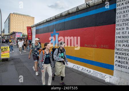 Fußgänger spazieren am 13. April 2024 in Berlin vorbei an Vaterland, einem markanten Wandgemälde an der East Side Gallery, entlang eines erhaltenen Abschnitts der Berliner Mauer. Das Werk des deutschen Künstlers Günther Schaefer verbindet symbolisch die Farben der deutschen Flagge mit dem Davidstern, der sich in der Mitte der israelischen Flagge befindet. Das Image wurde häufig mit politisch motivierten und antisemitischen Slogans ins Visier genommen, die die größeren Spannungen und die aktuelle Situation in Deutschland widerspiegeln, wo es seit 2023 zu einer Zunahme antisemitischer Vorfälle infolge des Krieges in Israel und Gaza kommt. Die Stockfoto