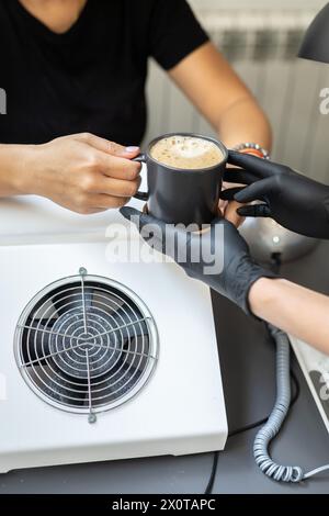 Kleinunternehmen, Leute und Servicekonzept - Frau gibt Kaffeetassen im Manikürsalon Stockfoto