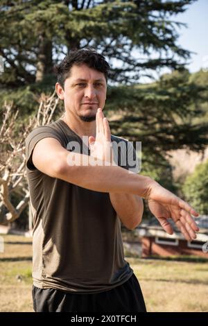 In einer vertikalen Aufnahme übt ein Mann mittleren Alters fleißig Kung Fu aus und zeigt seine Hingabe, diese alte Kampfkunst inmitten der se zu meistern Stockfoto
