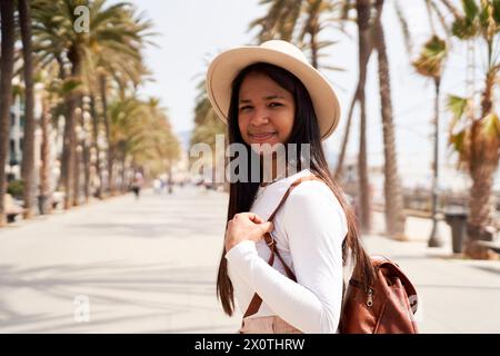 Porträt einer Afroamerikanerin, die in ihren Strandferien Tourismus macht, die Kamera lächelnd ansieht Stockfoto