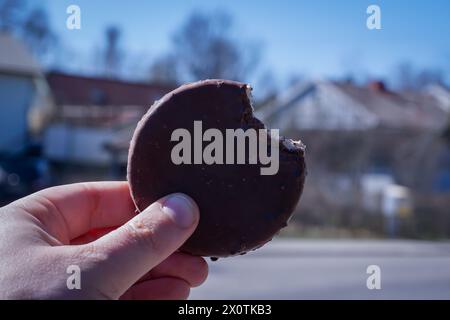 Abgeschnittene Hand, die Eis gegen eine Straße hält Stockfoto