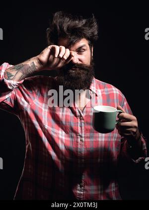 Happy Morning. Mans hält eine Tasse Kaffee. Morgentee. Guten Morgen. Mann mit Teetasse. Hipster-Mann mit einer Tasse Kaffee. Bärtiger Mann, der lächelt, hält Tasse Tee Stockfoto