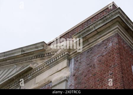 Beispiel für zerbröckelnde, sich verschlechternde dekorative Betonfertigteile, Merkmale, auf einem alten Backsteinschul-Gebäude. Stockfoto