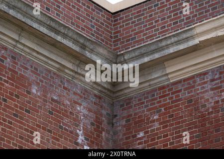 Beispiel für zerbröckelnde, sich verschlechternde dekorative Betonfertigteile, Merkmale, auf einem alten Backsteinschul-Gebäude. Stockfoto