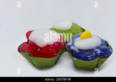 Nahaufnahme von 3 „umgedrehten“ thailändischen Khanom Tako-Desserts mit einer Vielzahl von Belägen - rote Rubinwasserkastanien (Tub Tim Grob), Butterfly-Erbsengelee, Sago Stockfoto