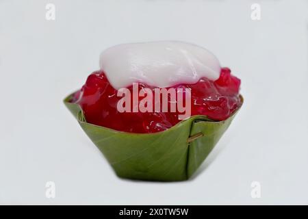 Nahaufnahme eines „umgedrehten“ thailändischen Khanom Tako Desserts mit roten Rubinen, Wasserkastanien (Tub Tim Grob) in einer Tasse mit Pandanblättern Stockfoto