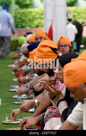 NOIDA, INDIEN - 13. APRIL: Gläubige nehmen Prasad in der Gemeindeküche (Langar) im Sektor 18 Gurudwara anlässlich von Baisakhi am 13. April 2024 in Noida, Indien ein. Baisakhi oder Vaisakhi, ein beliebtes Frühlingsfest, das den ersten Tag des Monats Vaisakh markiert, wird mit viel Enthusiasmus unter den Hindu-, Sikh- und buddhistischen Gemeinschaften gefeiert. Es ist der Beginn des Punjabi und Sikh Neujahrs, das in ganz Indien gefeiert wird, insbesondere in Punjab und Nordindien. Baisakhi wird am 13. April dieses Jahres beobachtet, was den Beginn der Erntesaison in Punjab einläutet. Es fällt am ersten Tag des Hindu Stockfoto