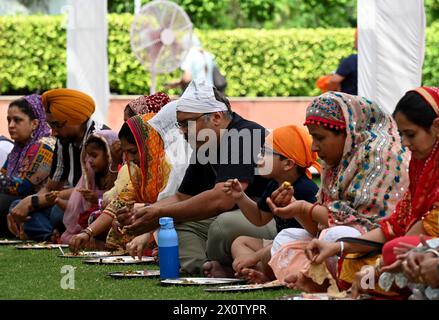 NOIDA, INDIEN - 13. APRIL: Gläubige nehmen Prasad in der Gemeindeküche (Langar) im Sektor 18 Gurudwara anlässlich von Baisakhi am 13. April 2024 in Noida, Indien ein. Baisakhi oder Vaisakhi, ein beliebtes Frühlingsfest, das den ersten Tag des Monats Vaisakh markiert, wird mit viel Enthusiasmus unter den Hindu-, Sikh- und buddhistischen Gemeinschaften gefeiert. Es ist der Beginn des Punjabi und Sikh Neujahrs, das in ganz Indien gefeiert wird, insbesondere in Punjab und Nordindien. Baisakhi wird am 13. April dieses Jahres beobachtet, was den Beginn der Erntesaison in Punjab einläutet. Es fällt am ersten Tag des Hindu Stockfoto