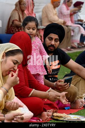 NOIDA, INDIEN - 13. APRIL: Gläubige nehmen Prasad in der Gemeindeküche (Langar) im Sektor 18 Gurudwara anlässlich von Baisakhi am 13. April 2024 in Noida, Indien ein. Baisakhi oder Vaisakhi, ein beliebtes Frühlingsfest, das den ersten Tag des Monats Vaisakh markiert, wird mit viel Enthusiasmus unter den Hindu-, Sikh- und buddhistischen Gemeinschaften gefeiert. Es ist der Beginn des Punjabi und Sikh Neujahrs, das in ganz Indien gefeiert wird, insbesondere in Punjab und Nordindien. Baisakhi wird am 13. April dieses Jahres beobachtet, was den Beginn der Erntesaison in Punjab einläutet. Es fällt am ersten Tag des Hindu Stockfoto