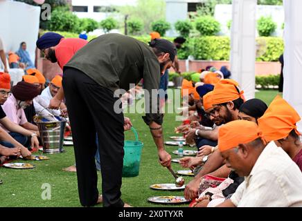 NOIDA, INDIEN - 13. APRIL: Gläubige nehmen Prasad in der Gemeindeküche (Langar) im Sektor 18 Gurudwara anlässlich von Baisakhi am 13. April 2024 in Noida, Indien ein. Baisakhi oder Vaisakhi, ein beliebtes Frühlingsfest, das den ersten Tag des Monats Vaisakh markiert, wird mit viel Enthusiasmus unter den Hindu-, Sikh- und buddhistischen Gemeinschaften gefeiert. Es ist der Beginn des Punjabi und Sikh Neujahrs, das in ganz Indien gefeiert wird, insbesondere in Punjab und Nordindien. Baisakhi wird am 13. April dieses Jahres beobachtet, was den Beginn der Erntesaison in Punjab einläutet. Es fällt am ersten Tag des Hindu Stockfoto