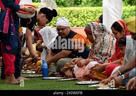 NOIDA, INDIEN - 13. APRIL: Gläubige nehmen Prasad in der Gemeindeküche (Langar) im Sektor 18 Gurudwara anlässlich von Baisakhi am 13. April 2024 in Noida, Indien ein. Baisakhi oder Vaisakhi, ein beliebtes Frühlingsfest, das den ersten Tag des Monats Vaisakh markiert, wird mit viel Enthusiasmus unter den Hindu-, Sikh- und buddhistischen Gemeinschaften gefeiert. Es ist der Beginn des Punjabi und Sikh Neujahrs, das in ganz Indien gefeiert wird, insbesondere in Punjab und Nordindien. Baisakhi wird am 13. April dieses Jahres beobachtet, was den Beginn der Erntesaison in Punjab einläutet. Es fällt am ersten Tag des Hindu Stockfoto