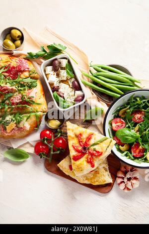 Vollständiger Tisch mit italienischen Gerichten auf Tellern Pizza, Pasta, Ravioli, Salat und Focaccia auf weißem Hintergrund. Draufsicht Stockfoto