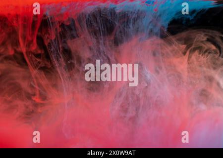 Wolken von rotem und blauem Rauch auf schwarzem Hintergrund, Wolken von Farbe im Wasser, Aquarium, abstrakter Hintergrund, Textur Stockfoto