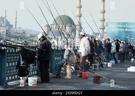 Geschäftige Szene mit lokalen Fischern, die die Galatabrücke mit Istanbuls Skyline im Hintergrund ablegen Stockfoto