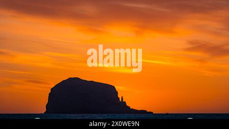 Firth of Forth, Schottland, Großbritannien, 14. April 2024. Wetter in Großbritannien: Sonnenaufgang über dem Bass Rock. Zu dieser Jahreszeit ist es möglich, einen Blick auf den Sonnenaufgang hinter der Tölpellerkolonie von der Ostlothianischen Küste vor einem leuchtenden orangen Himmel zu werfen. Quelle: Sally Anderson/Alamy Live News Stockfoto