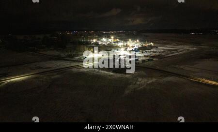 Drohnenfotografie von Metall-Recycling-Anlagen in der Entfernung während der winterlichen bewölkten Nacht Stockfoto