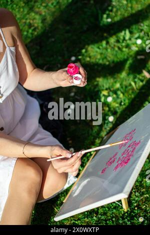 Eine Künstlerin malt ein Bild mit rosa Farben. Stockfoto