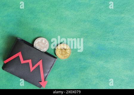 Menschliche Hand, die schwarz eine Brieftasche mit Bitcoin hält und unten roten Pfeil und Münze innen. Kryptowährungen, Bärenlauf und Preissenkungskonzept. Stockfoto