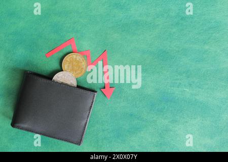 Menschliche Hand, die schwarz eine Brieftasche mit Bitcoin hält und unten roten Pfeil und Münze innen. Kryptowährungen, Bärenlauf und Preissenkungskonzept. Stockfoto