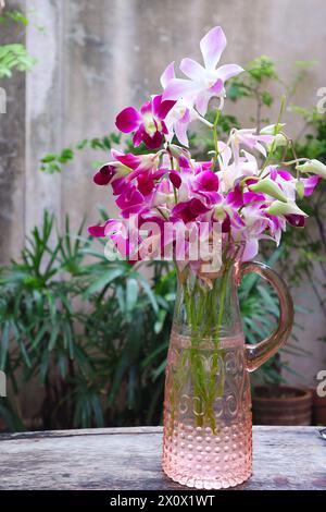 Ein Haufen lila rosa Dendrobium Orchideenblumen in einer Glasvase Stockfoto