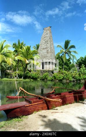 Hawaii, USA, ca. 1993. Der religiöse Tempel von Fidschi wird im Polynesian Cultural Center ausgestellt. Ein Auslegerkanu am Ufer eines Flusses. Stockfoto