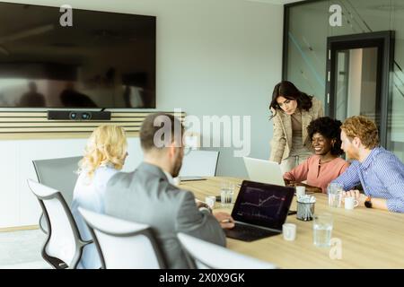 Eine multikulturelle Gruppe von Fachleuten arbeitet an einem Konferenztisch mit digitalen Geräten zusammen Stockfoto