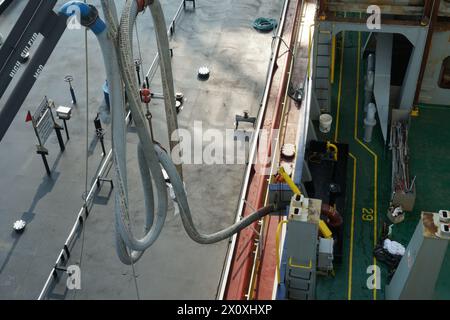 Kraftstoffschlauch des Bunkerkahns, der am Kran befestigt und an das Containerschiff in der Bunkerstation mit Ventilen und Verteilern angeschlossen ist. Stockfoto