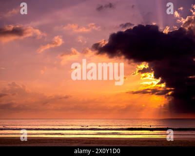 Fantastischer Hintergrund des Sonnenuntergangshimmels mit Farbverlauf und wunderschönen Sonnenstrahlen hinter dunkler Wolke über dem Meerwasser. Sommer Sandstrand Landschaft am Abend t Stockfoto