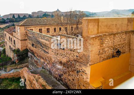 Altes Gebäude mit Steinmauern, Fenstern und braunen Giebeldächern auf einem Hügel in felsigen Bergen, nebliger grauer Himmel im Hintergrund, sonniger Tag in Spanien Stockfoto