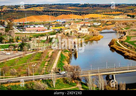 Blick aus der Vogelperspektive auf das Tal mit dem Fluss Tejo am Stadtrand von Toledo, Hügel mit landwirtschaftlich genutztem Land im Hintergrund, Fahrzeugbrücke über den Fluss, Gebäude, Stockfoto