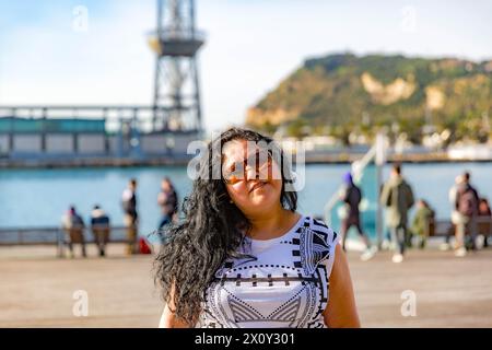 Porträt einer molligen lateinamerikanischen Frau auf der Stadtpromenade, dem Cable Car Tower und dem Berg in unscharfem Hintergrund, langen schwarzen Haaren, Sonnenbrillen und Stockfoto