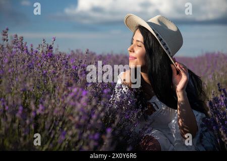 Schöne junge Frau, die die Lavendelblumen bei Sonnenuntergang bewundert. Stockfoto