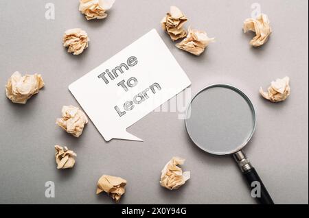 Ein weißes Schild mit der Aufschrift Time to Learn ist von geschreddertem Papier umgeben. Das geschredderte Papier ist um das Schild herum verstreut, wodurch ein s entsteht Stockfoto